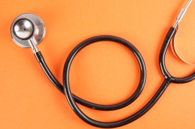 Tıbbi kavramı stetoskop, turuncu zemin üzerine izole şırınga ile. Kopya alanı