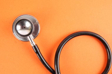 Tıbbi kavramı stetoskop, turuncu zemin üzerine izole şırınga ile. Kopya alanı