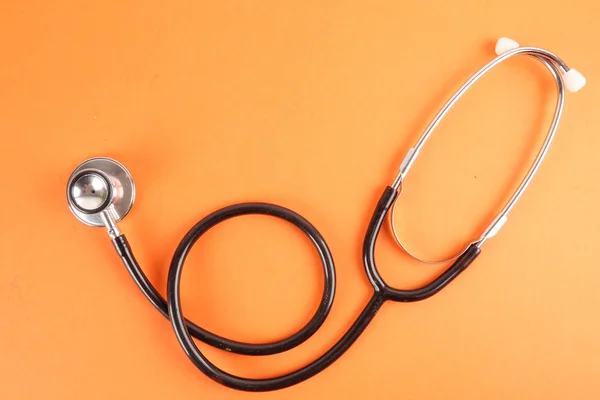 Tıbbi kavramı stetoskop, turuncu zemin üzerine izole şırınga ile. Kopya alanı