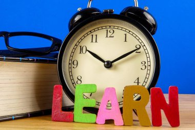 Eğitim kavramı kitap, çalar saat, cam ile kelime öğrenin.