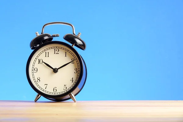 Reloj Despertador Negro Superficie Madera Contra Fondo Azul —  Fotos de Stock