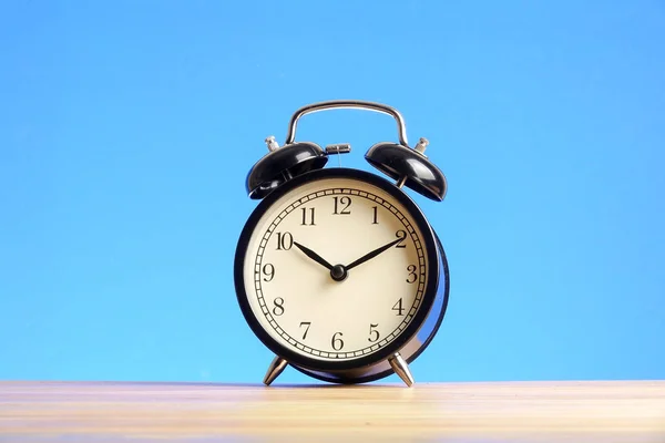 Reloj Despertador Negro Superficie Madera Contra Fondo Azul — Foto de Stock