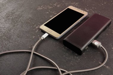Akıllı telefon ve powerbank rustik siyah arka plan üzerinde.