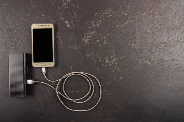 素朴な黒の背景にスマートフォンとパワーバンク — ストック写真