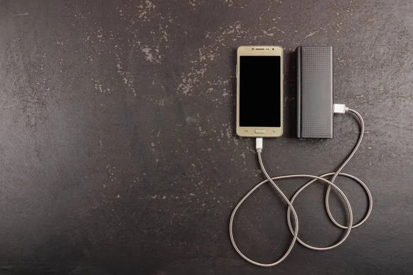 素朴な黒の背景にスマートフォンとパワーバンク — ストック写真