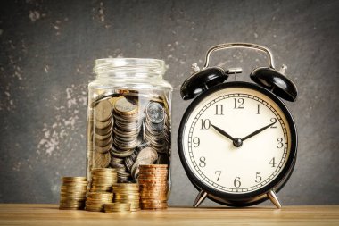 Siyah arkaplan üzerinde ahşap bir masa üzerinde bozuk para yığını ile tasarruf kavramı.