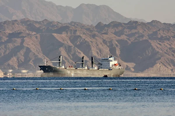 Kargo gemisi gün ışığında yardım dağlarının arka planına karşı.