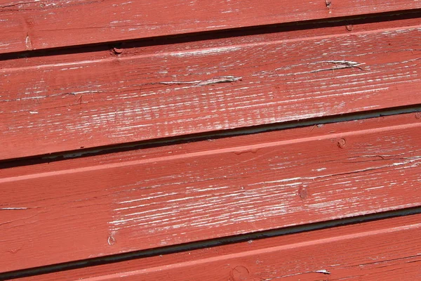 Parlak bahar güneşinde kırmızıya boyanmış bir evin duvarının ahşap yapısı.