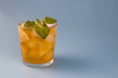 Mavi arka planda limon ve nane aromalı siyah buzlu çay.