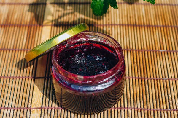 Kuşüzümü reçeli kavanozu, doğanın arka planına ve böğürtlen çalısına karşı. Currant Köyü