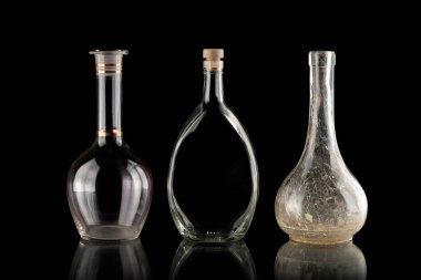 Glassware on a black isolated background. Decanters of various shapes. A group of transparent items. The reflection under the objects. Old household items. Fragile dishes. Liquid containers. clipart
