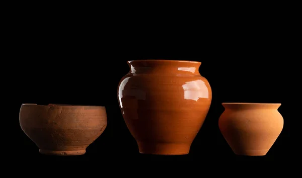 Kapalı alan çiçekleri ya da yemek pişirmek için kil kaplar. Siyah, izole bir arka planda birkaç eski mutfak gereçleri. Halk sanatı ögeleri.