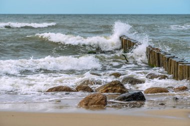 Baltık Denizi 'nin fırtına dalgaları kumlu kıyıları kaplıyor. Şalter ve kayalardan fışkıran su. Sert deniz elementleri.