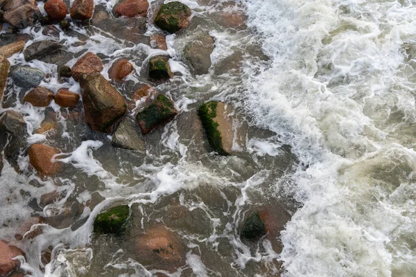 海の水は大きな海岸岩を洗う 湿った光沢のある岩の上で波が砕ける 水と岩肌の質感 — ストック写真
