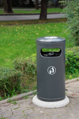 Kaldırımdaki siyah çöp tenekesi. Çöp depolamak için metal kova. Şehir sokaklarında çevre temizliği.