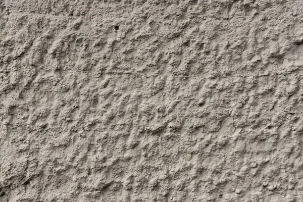 Grey decorative concrete wall of the building front. The bumpy texture of the cement surface.