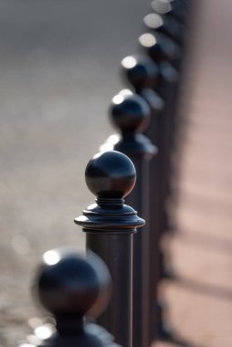 Yaya kaldırımı, yol kenarından siyah park karşıtı sütunlarla ayrılır. İnsanlar kaldırımda yürüyor sokak lambalarının altında.