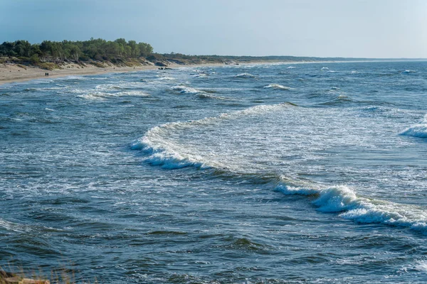 砂浜の海岸線は地平線まで伸びている 青い海の波が海岸を越えて人々が歩く — ストック写真