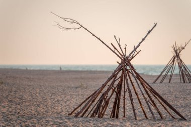 Sahilde ağaçtan yapılmış bir çadır. Parmaklıklar insanların plajda dinlenmesi için koni şeklinde katlandı. Deniz kıyısındaki ahşap sahil binaları.