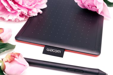 Kirov, Rusya - 27 Haziran 2020; Wacom grafik tableti ve beyaz arka planda pembe şakayıklı bir kalem. Yazı için alanı kopyala, sığ alan derinliğine sahip seçici odak