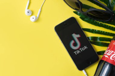 Kirov, Rusya - 28 Haziran 2020: Sarı arka planda bir yaprak, kulaklık ve Coca-Cola ile akıllı telefon ekranında Tik Tok uygulama simgesi. Tiktok Sosyal medya ağı. Boşluğu, düzlüğü, üst görünümü kopyala