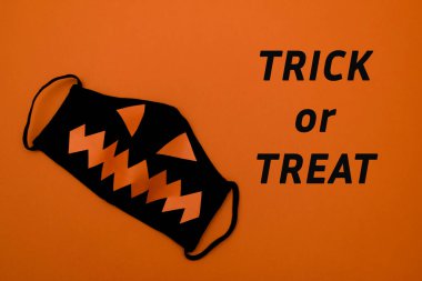 Turuncu arka planda turuncu gözlü ve ağzı olan siyah koruyucu maske. Turuncu arkaplanda 