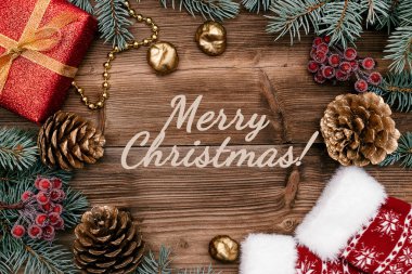 Kırmızı hediye kutusundan yapılmış Noel çerçevesi, mavi köknar ağacı dalları, altın koniler, koyu ahşap arka planda böğürtlen ve çoraplar. Merry Noeli! Tatil konsepti, üst görünüm, düz yatak