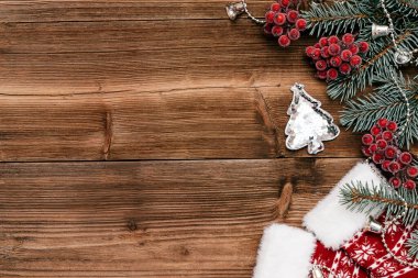 Noel çerçevesi mavi köknar ağacı dalları, viburnum üzümleri, oyuncak Noel ağacı ve koyu ahşap arka planda çoraplardan yapılmıştır. Noel arkaplanı. Yazı, üst görünüm, düz görünüm için boşluk kopyala