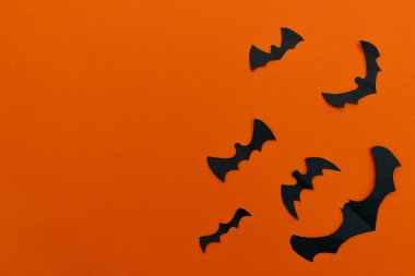 Turuncu arkaplandaki siyah yarasalar. Cadılar Bayramı kavramı. Boşluğu kopyala, düz yat, üst görüş.