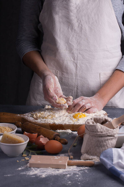 Young woman baker prepares the dough on table
