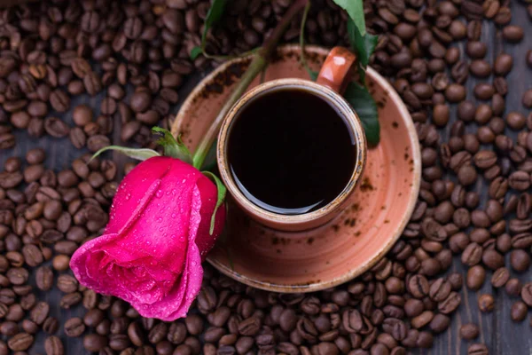 Кружка черного кофе и розы на жареных кофейных зерен — стоковое фото