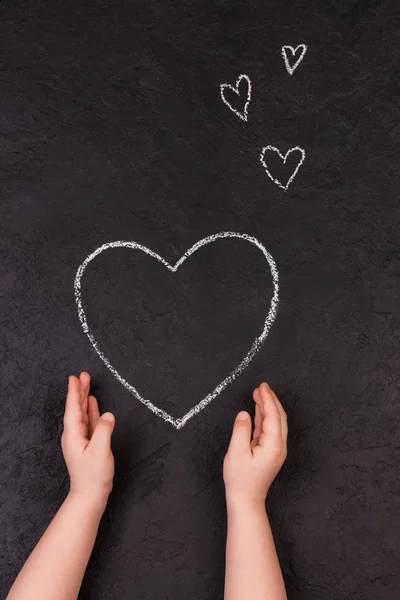 Hand tekenen hart met krijt. Schattig klein meisje met symbool van de liefde. — Stockfoto
