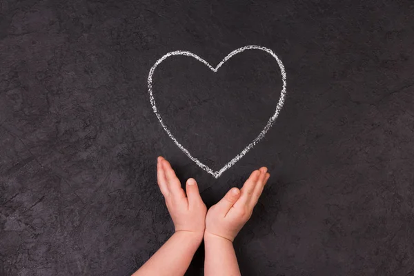 Hand tekenen hart met krijt. Schattig klein meisje met symbool van de liefde. — Stockfoto