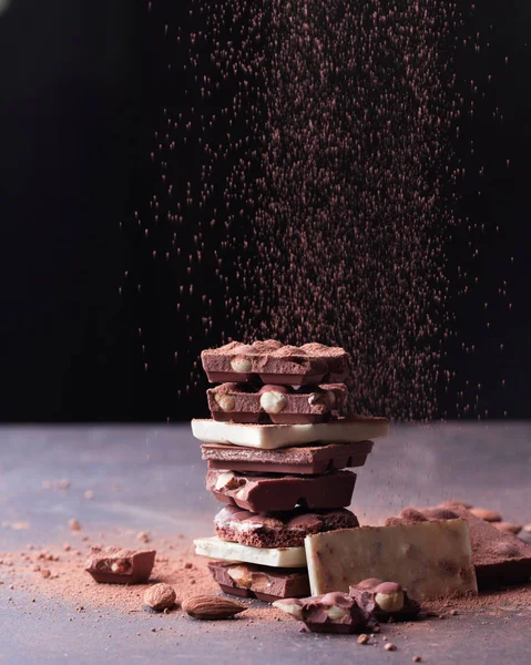 Stapel Dunkler Schokoladenstücke Und Mandeln Auf Dunklem Hintergrund — Stockfoto