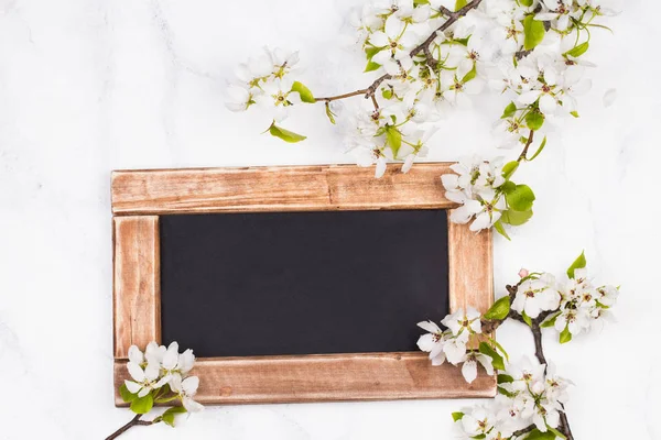 Flores de maçã e tábua de giz na superfície de madeira branca. Cartão de felicitações Páscoa . — Fotografia de Stock