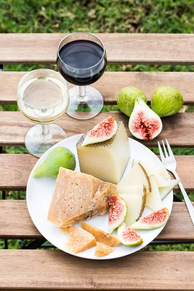 Käse, Feigen und Rot- und Weißweingläser auf einem Holztisch. — Stockfoto