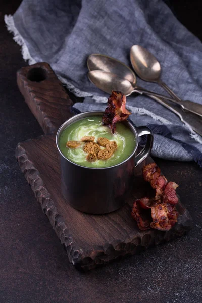Broccoli soup served in rustic mug on a kitchen cutting board. — Stock Photo, Image