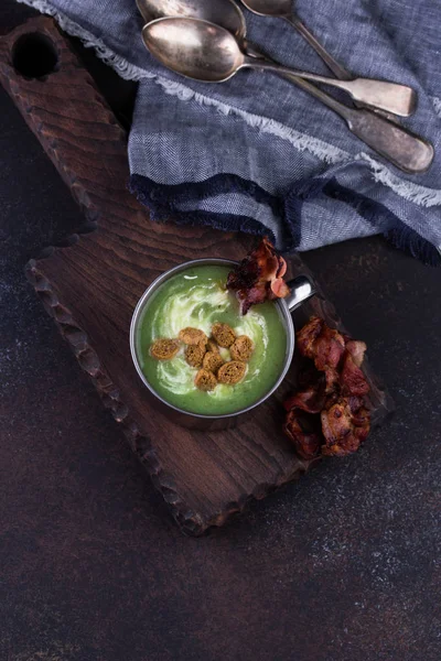 Broccoli soup served in rustic mug on a kitchen cutting board. — Stock Photo, Image