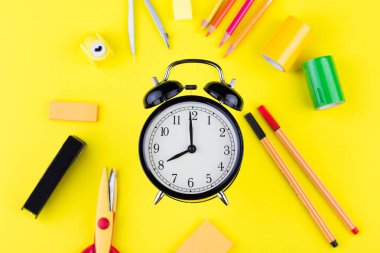 Okul sabit arasında çalar saat. Sarı arka planda üst görünüm
