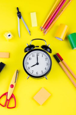 Okul sabit arasında çalar saat. Sarı arka planda üst görünüm