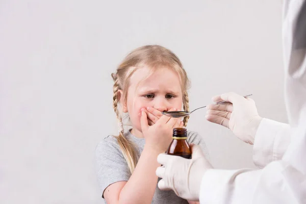 Маленька мила дівчинка не хоче отримати ложку ліків сиропу для пиття рідини . — стокове фото