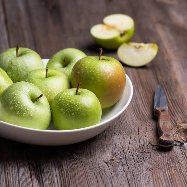 Green organic healthy apples in bowl on wooden board. Healthy food — Stock Photo, Image