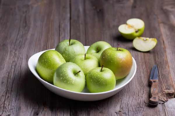 Green organic healthy apples in bowl on wooden board. Healthy food — Stock Photo, Image