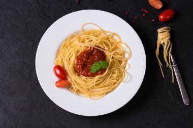 Lezzetli iştah açıcı klasik İtalyan spagettisi domates soslu makarna ve koyu tabakta fesleğen..