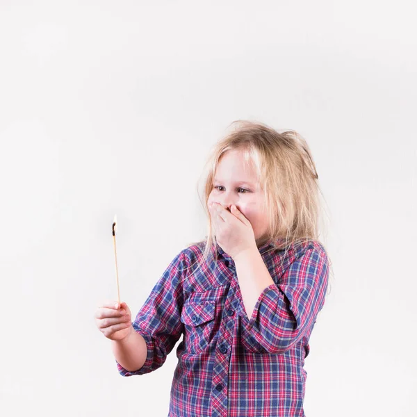 Excited wide eyed female child wearing plaid shirt yelling with flaming match