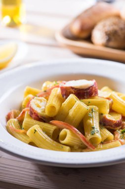 Lokantada servis edilen bir tabakta domatesli makarna ile ıstakoz. Organik deniz ürünleri yemeği: sağlıklı ıstakoz eti, domates ve taze otlu makarna, ahşap bir tabakta yakın plan.. 