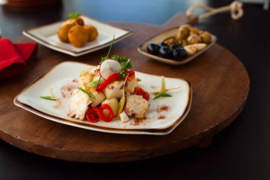 Bir restoranda servis edilen masada sebze doğranmış bir tabakta ahtapot salatası. Izgara ahtapot, patates ve sebzeli aperatif..