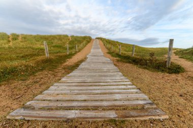 Kum tepelerinin üzerinde tahta patika. Fransa 'nın Atlantik kıyısındaki tahta patika..