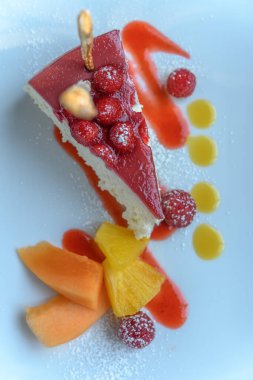 Ahşap bir masada ahududu reçelli cheesecake. Dilimlenmiş peynirli kek..