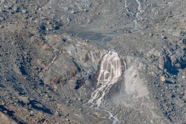 Kayalar ve enkazlarla çevrili, buzullarda çağlayan sular. Bu doğal olay, güneşli bir günde gözlemlenen buzun erimesi sonucu meydana gelir. Gornergletscher, Zermatt, valais, Alps, Swiss.